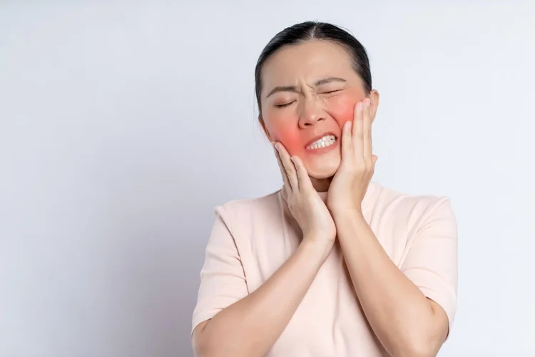 Asian lady suffering from toothache at both sides of her mouth.