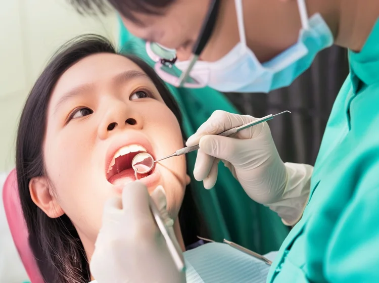 Dentist examining a young Singaporean patient’s teeth as part of a consultation and personalised assessment for Invisalign treatment.
