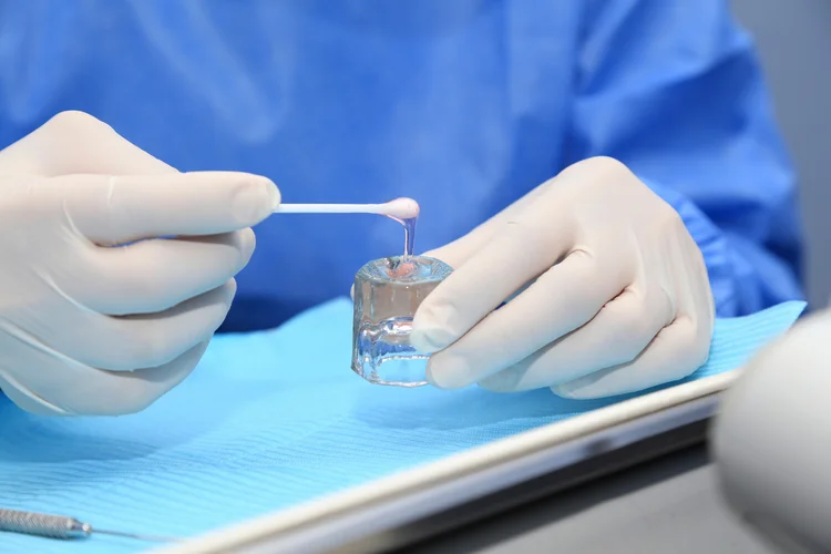 Dentist preparing fluoride gel for application to strengthen enamel and prevent cavities.