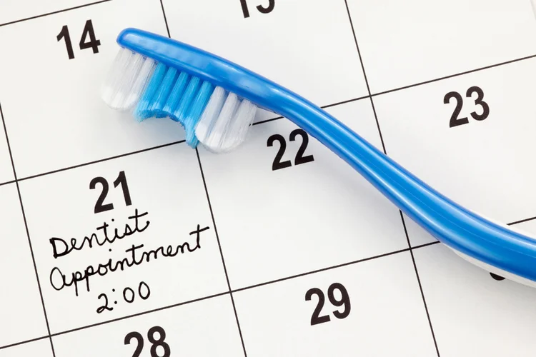 Toothbrush placed on calendar marking appointment for regular fluoride treatment.