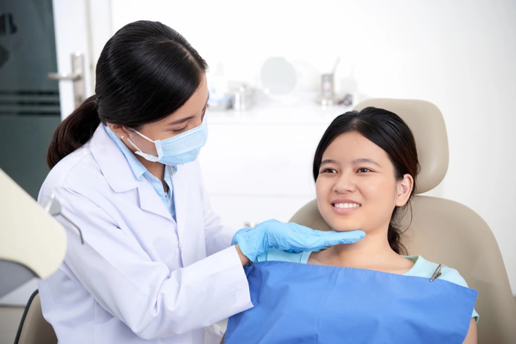 Dentist instructing her patient to adjust her jaw to a certain position for dental inspection.