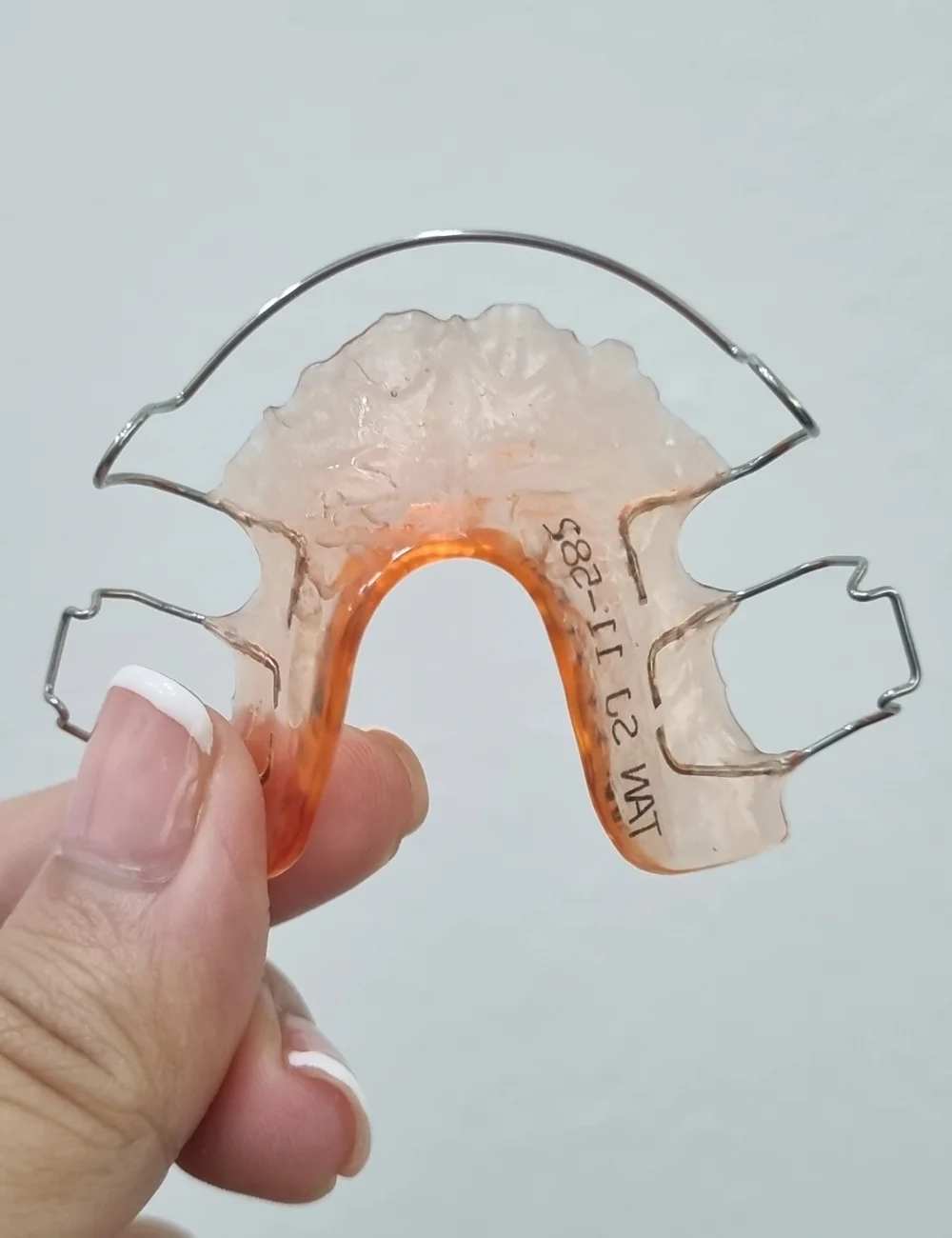 Hawley dental retainers held in hand.