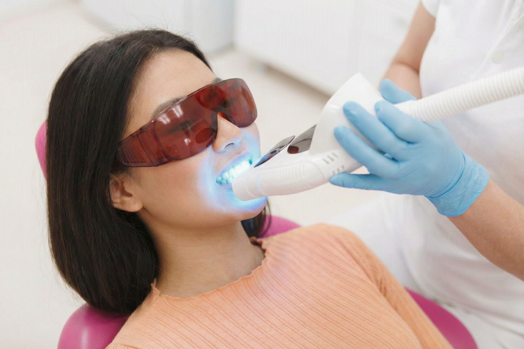 Woman receiving professional in-clinic teeth whitening treatment with LED light.