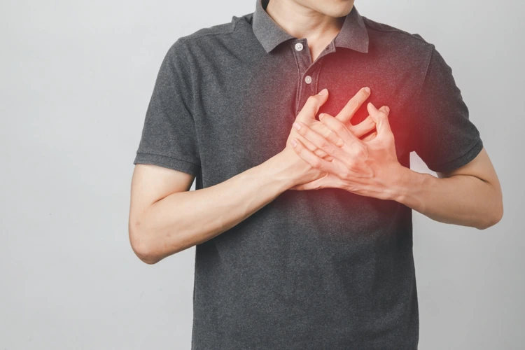 Man clutching his chest area after feeling pain and discomfort in his heart.