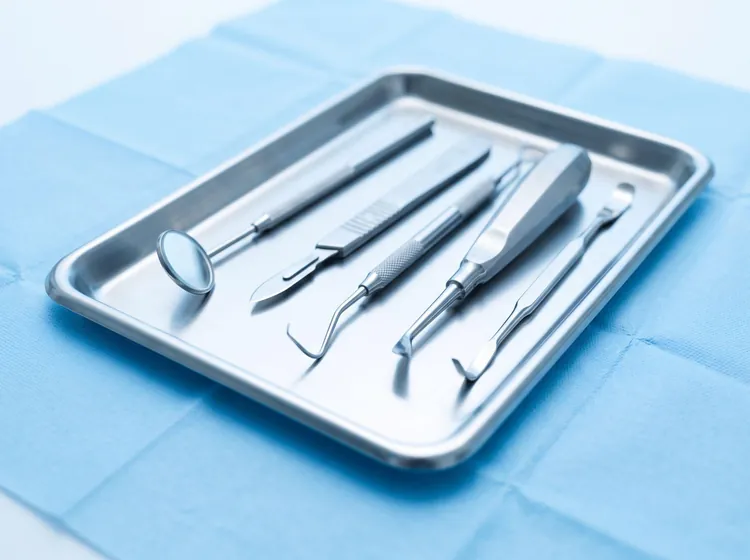 Sterile surgical instruments laid out on a tray before a dental procedure.