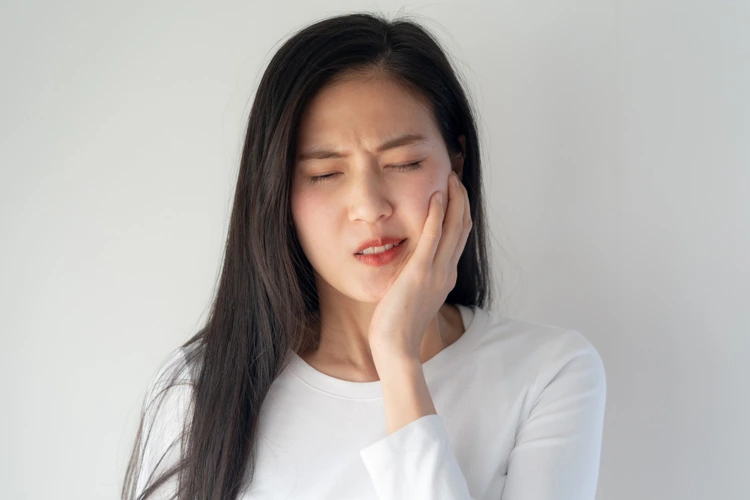 Lady touching her left cheek and feeling toothache in that area.
