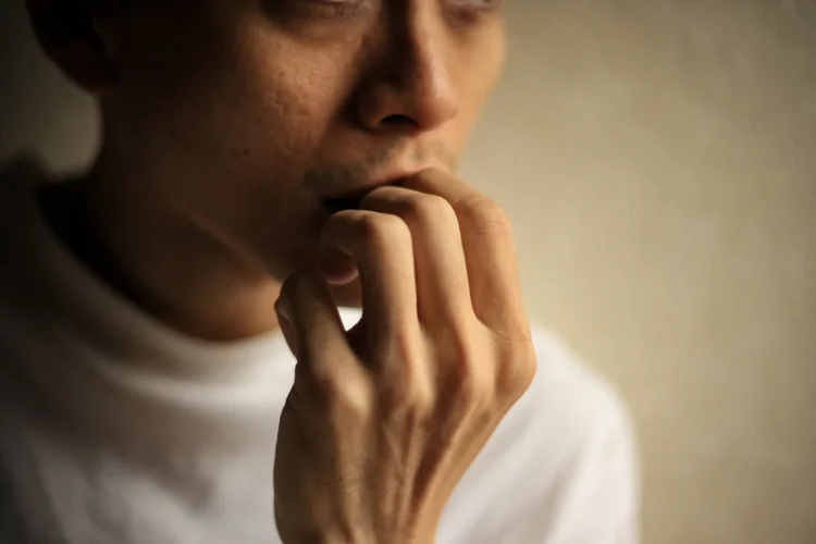 Singaporean man with an overbite partly caused by the habit of nail-biting, leading to teeth wear and affecting tooth growth.