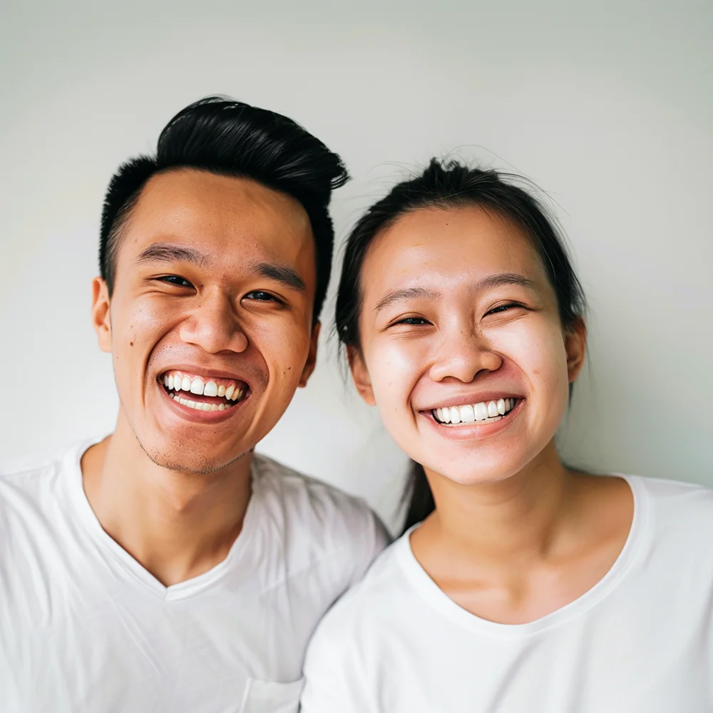 Singaporean young adults feeling confident and smiling widely, showing off their brighter smiles after regular dental check-ups for teeth scaling and polishing.