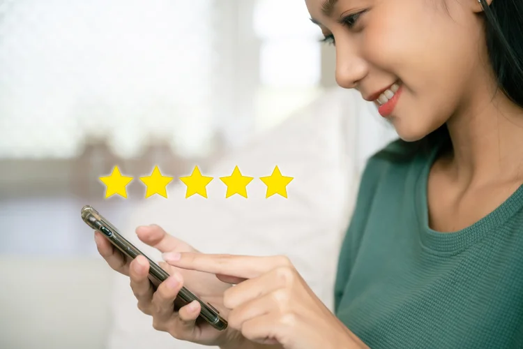 Smiling woman leaving a five-star online review for a dental clinic in Singapore after a positive and caring treatment experience.