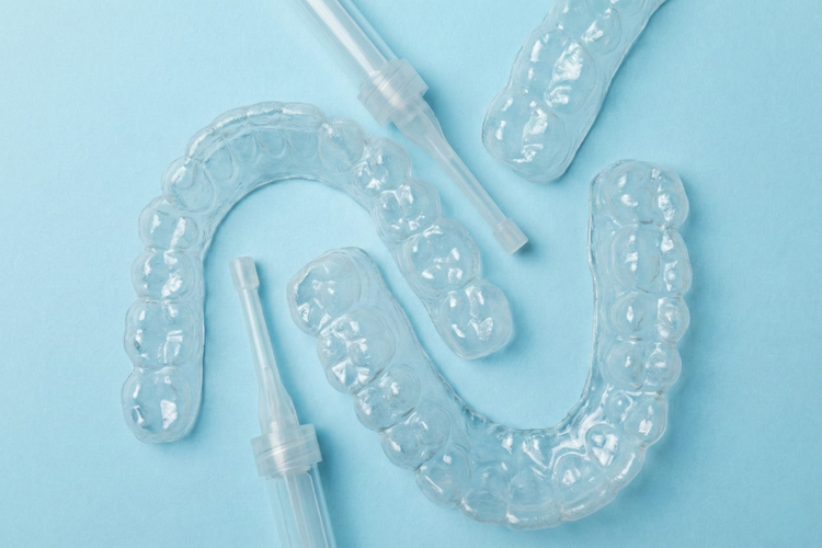 Custom-fitted whitening trays and gel syringes for take-home teeth whitening.