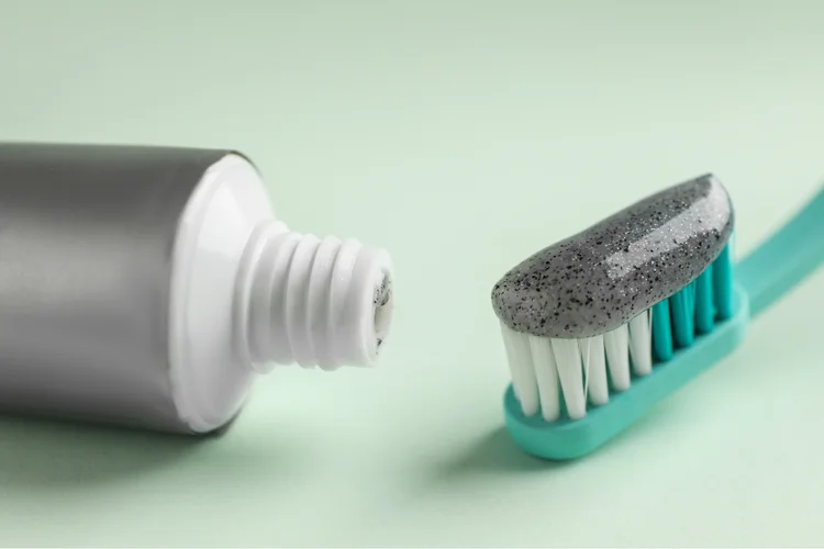 Toothbrush with toothpaste containing activated charcoal for teeth whitening, utilizing its adsorptive properties and porous structure to bind to surface stains for effective removal.