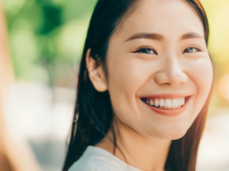 Young Asian woman smiling radiantly and confidently after receiving teeth veneers at True Dental Studio.